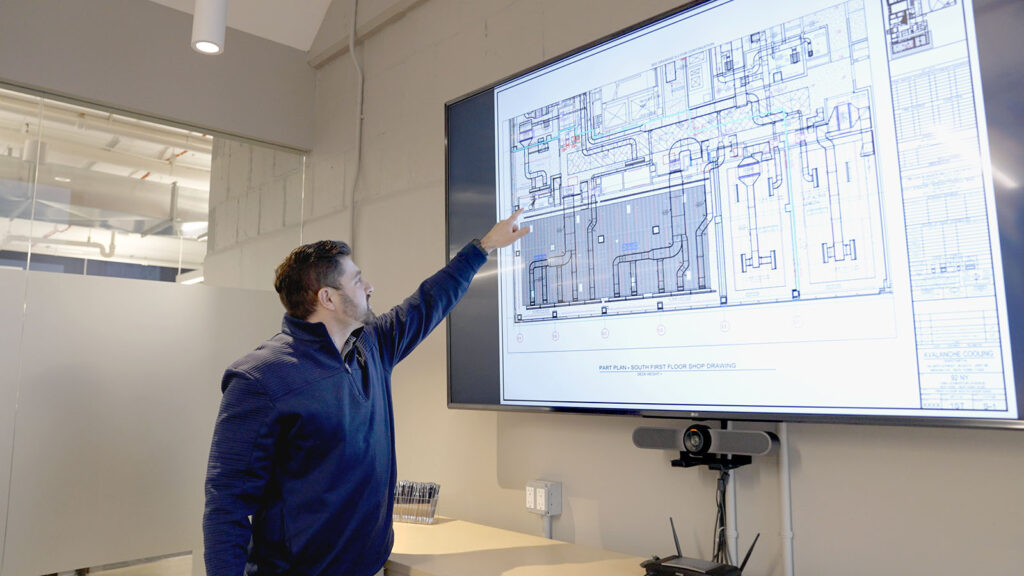 Employee reviewing mechanical HVAC design drawings on a large screen