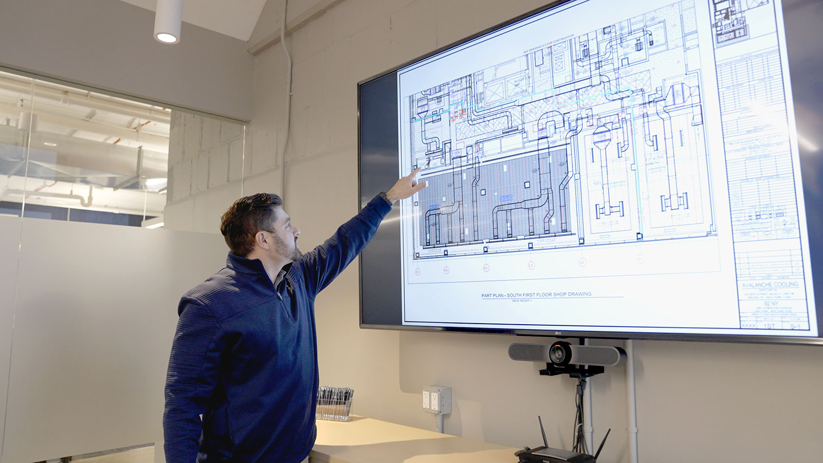 Employee reviewing mechanical HVAC design drawings on a large screen